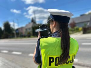 Policjanci oraz  ratownik na tle radiowozu