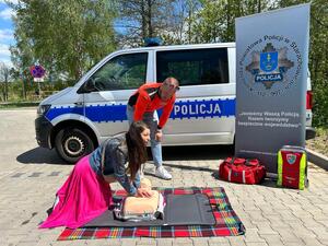Policjanci oraz  ratownik na tle radiowozu
